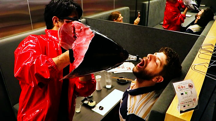 A guest drinking sake poured through the tuna head