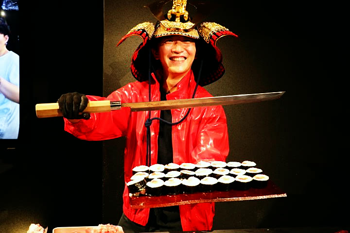 The host in a samurai helmet with the tuna knife and a tray of SHOGUN rolls