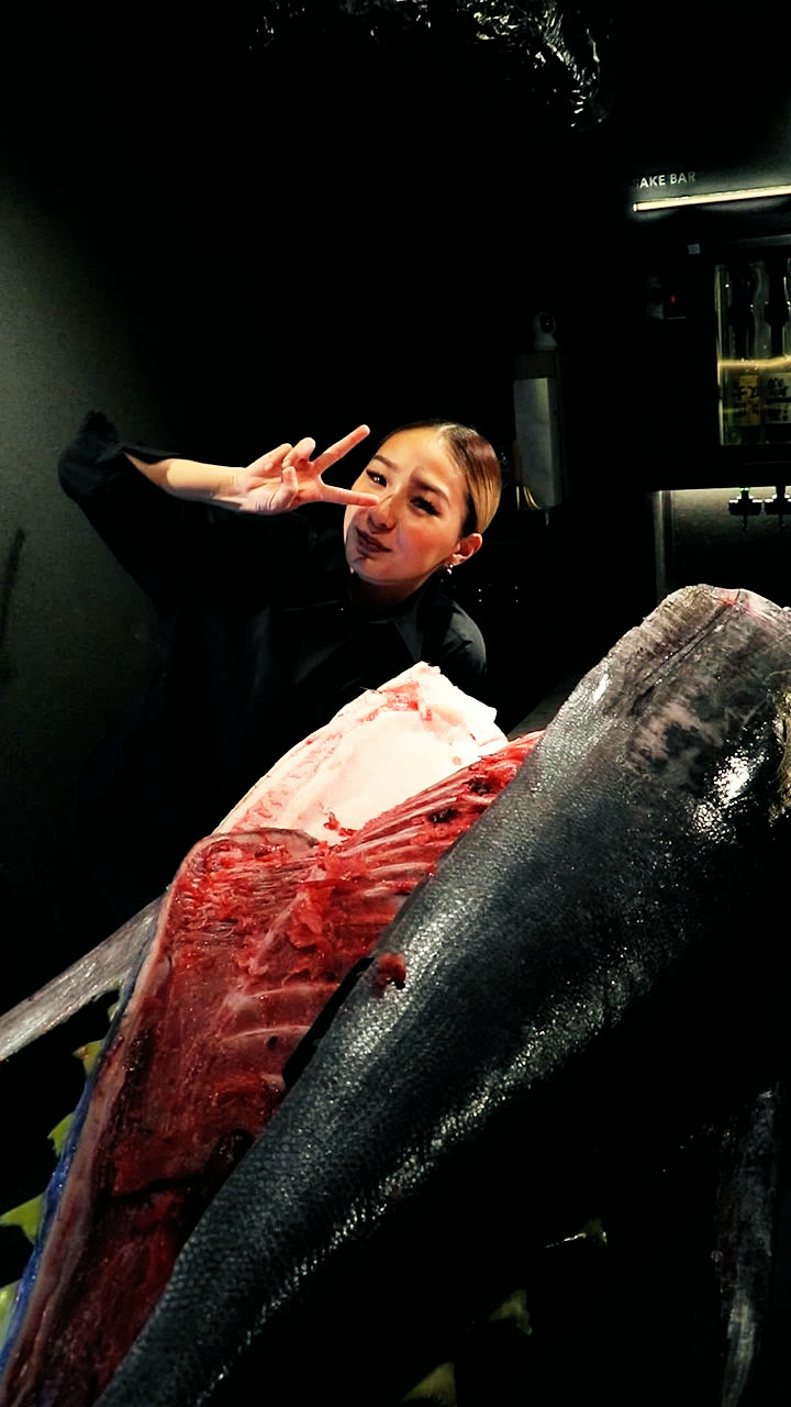 A member of the team beside a tuna being cut