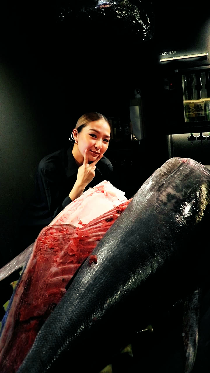 A member of the team beside a tuna being cut